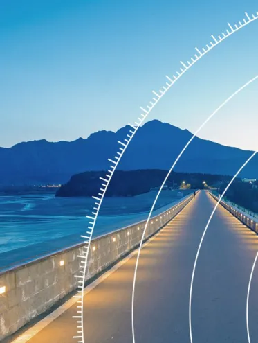 a long road with a body of water and mountains in the background