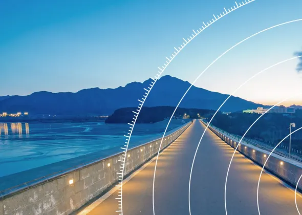 a long road with a body of water and mountains in the background