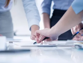 Eine Nahaufnahme der Hand einer Person, die auf ein Blatt Papier schreibt