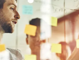 Ein Mann, der mit Haftnotizen auf eine Glaswand schaut