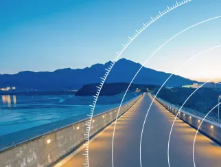 a long road with a body of water and mountains in the background