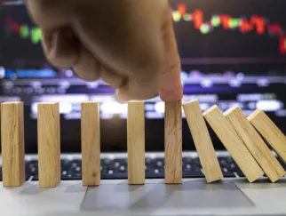 a hand stopping dominoes on a laptop